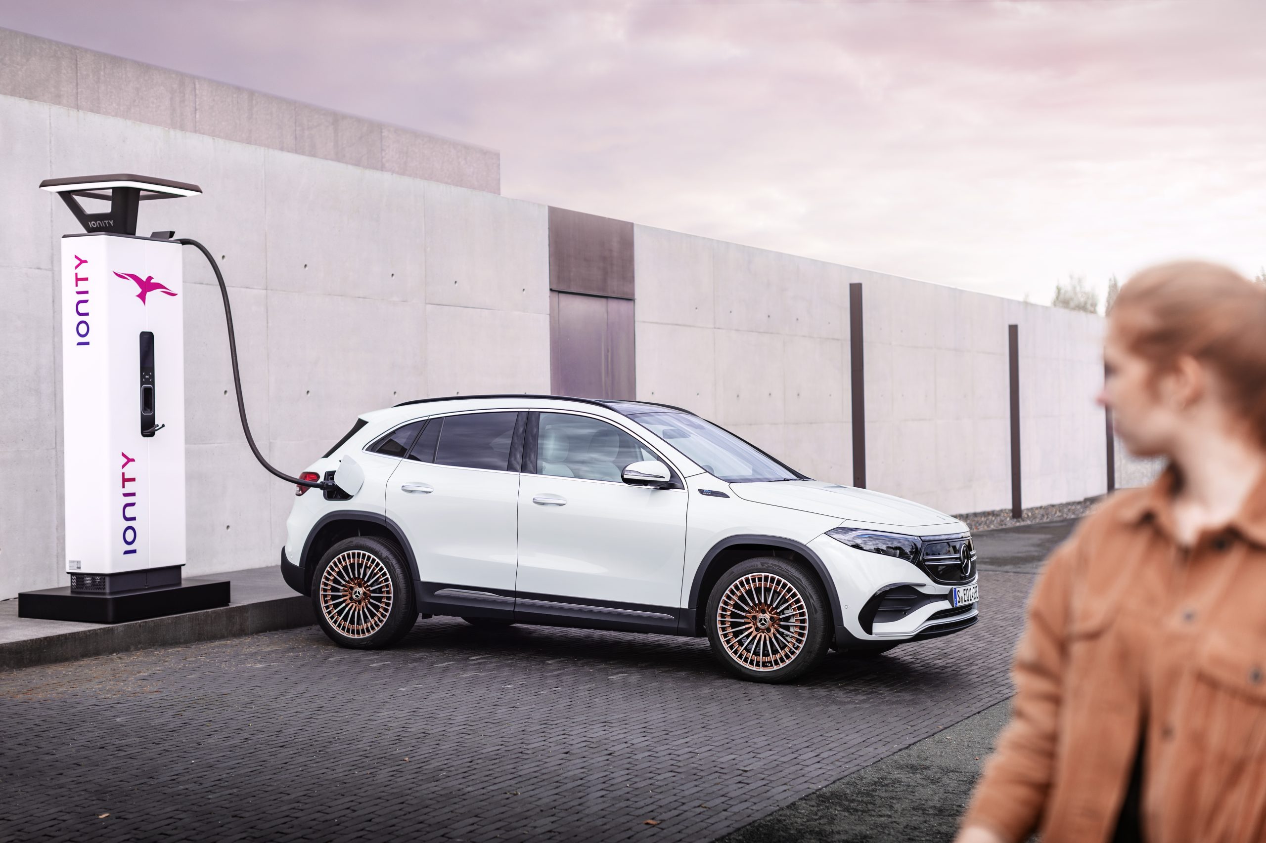 Woman charging her Mercedes EQA at a public charging point